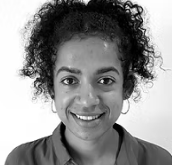 Black and white portrait of a young woman with curly hair smiling at the camera.