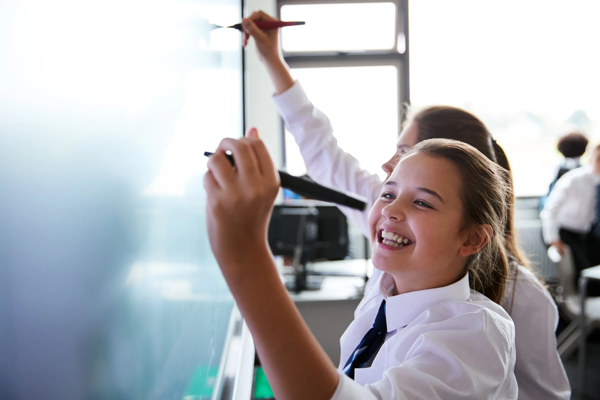 School children in uniform working at a whiteboard in classroom