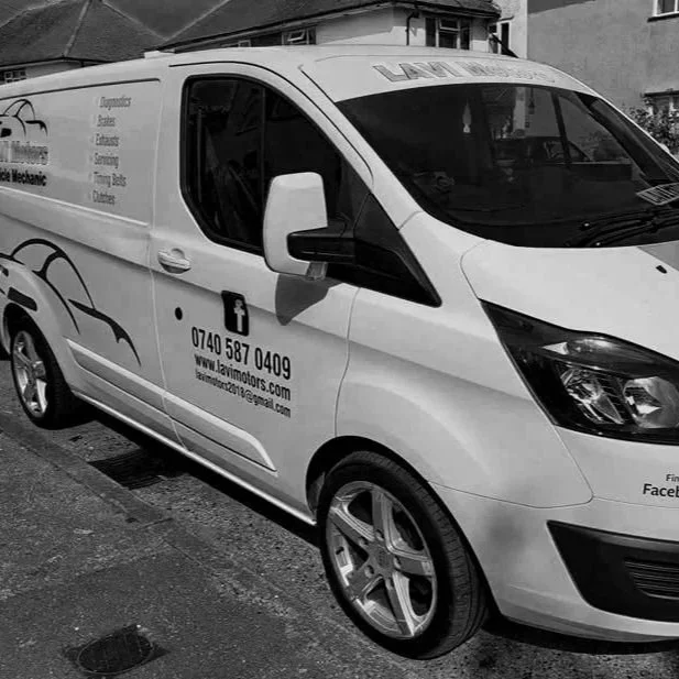 Side view of a white delivery van parked on a street, with text and graphics advertising a plumbing business, including a phone number, website, Facebook, and email contact information.