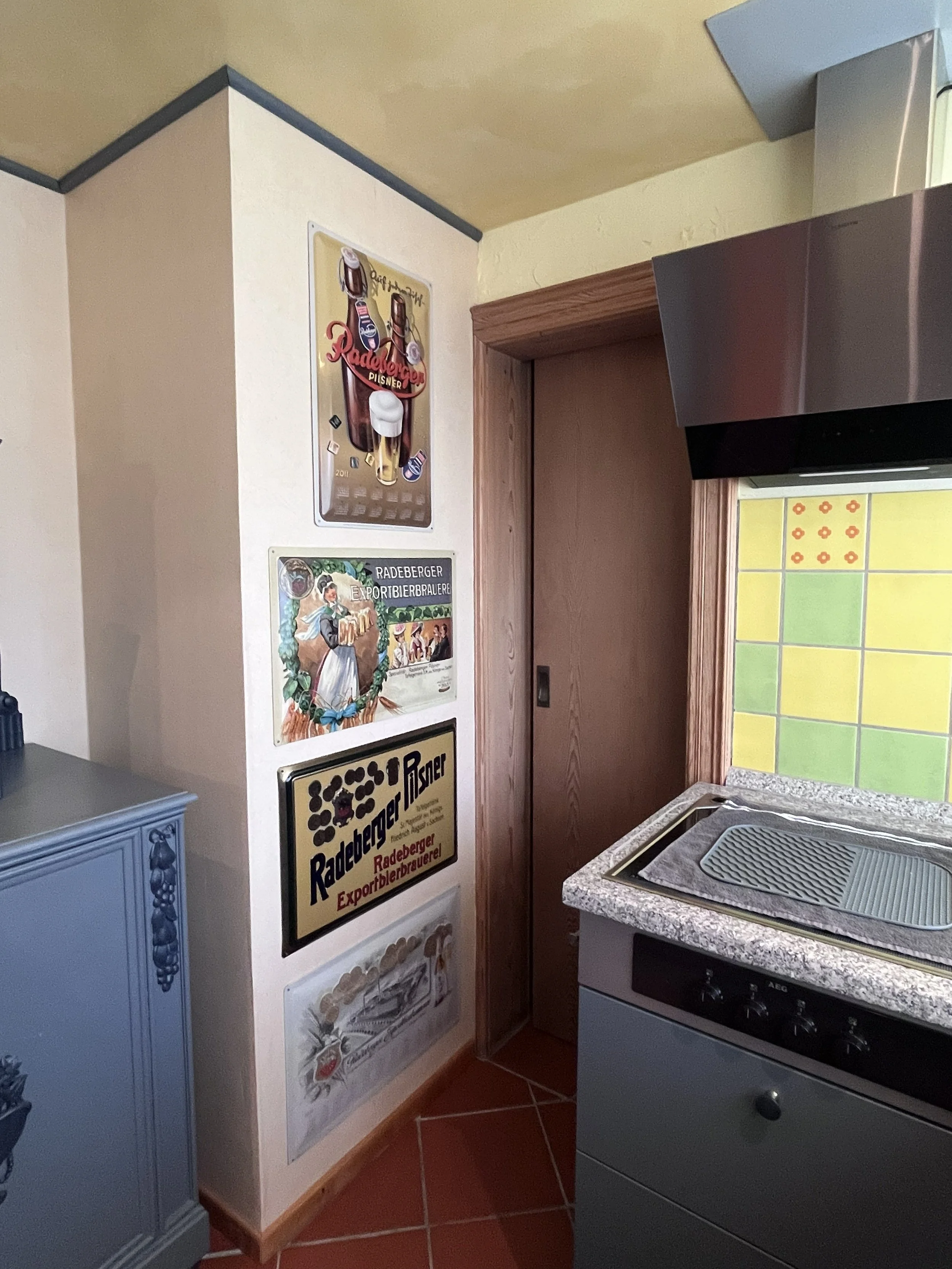 Küche der Ferienwohnung Radeberg mit nostalgischen Fliesen und Radeberger Werbeschild