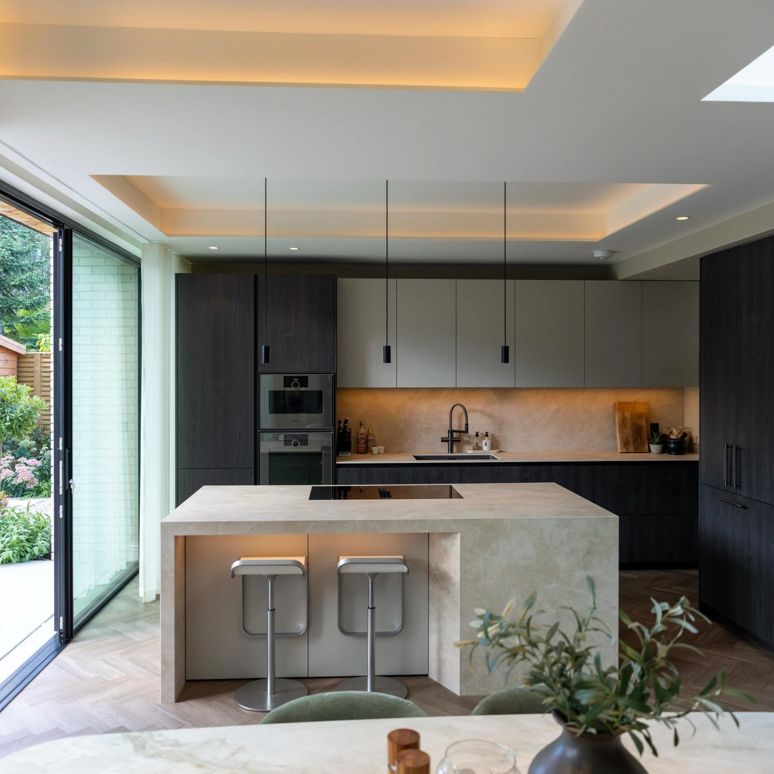 A seamless balance of architecture, materials and light.

Rich timber cabinetry, beautifully textured stone and warm architectural lighting bring depth and sophistication to this contemporary kitchen.

Expansive glazing blurs the boundaries between i