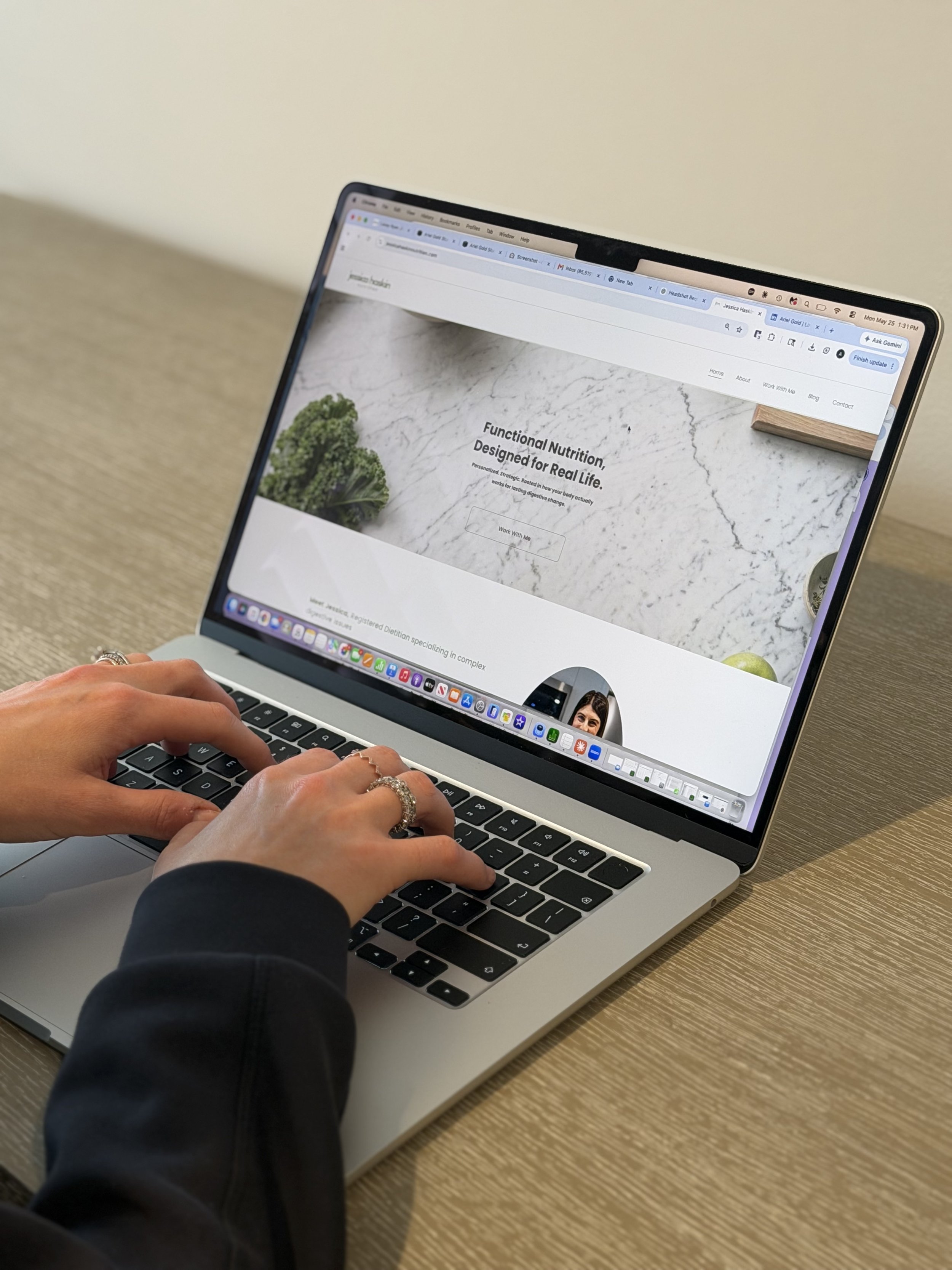 A person using a laptop with a web browser open showing a website about functional nutrition, with a marble background and a small piece of wood on the top right corner.