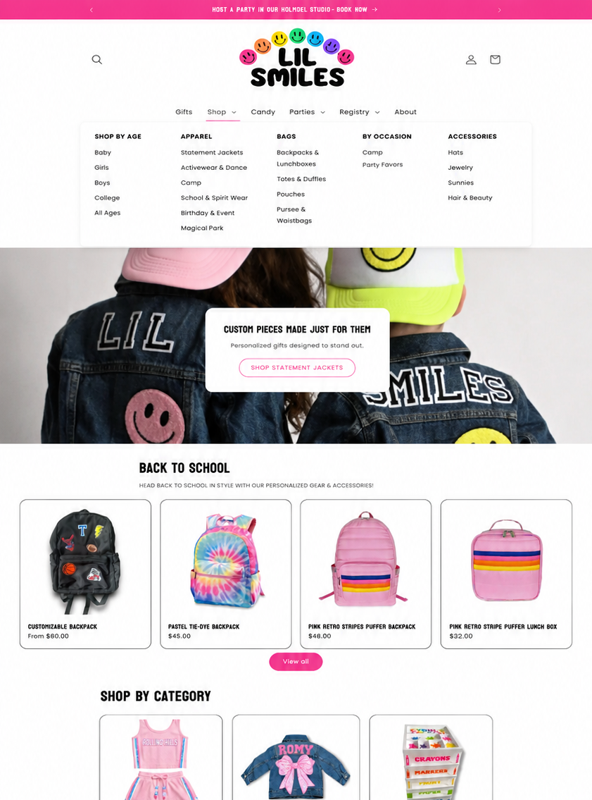 Homepage of Lil Smiles children's clothing online store with navigation menu, promotional banner, and product images of backpacks, lunch boxes, and apparel.