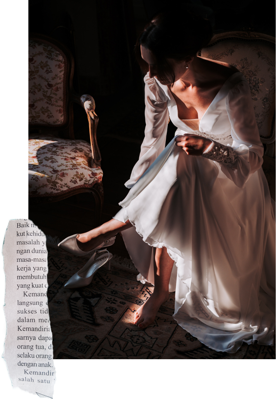 Une femme habillée en robe de mariage blanche ajuste ses chaussures à talons, assise sur un tapis, près d'une chaise ancienne à motif floral.