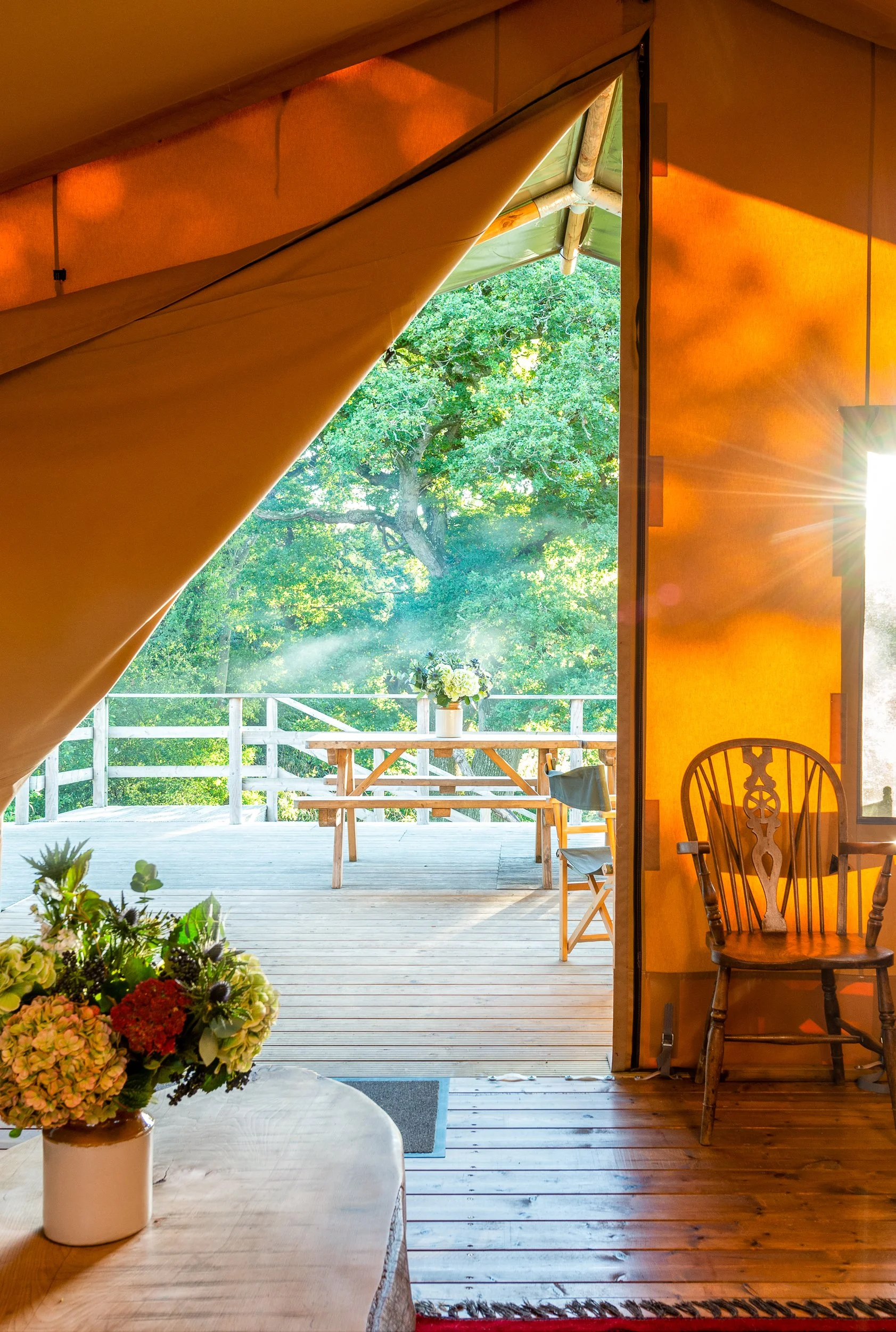 Interior view from a safari tent at Stock Gaylard, looking out towards the outdoor seating area and countryside.