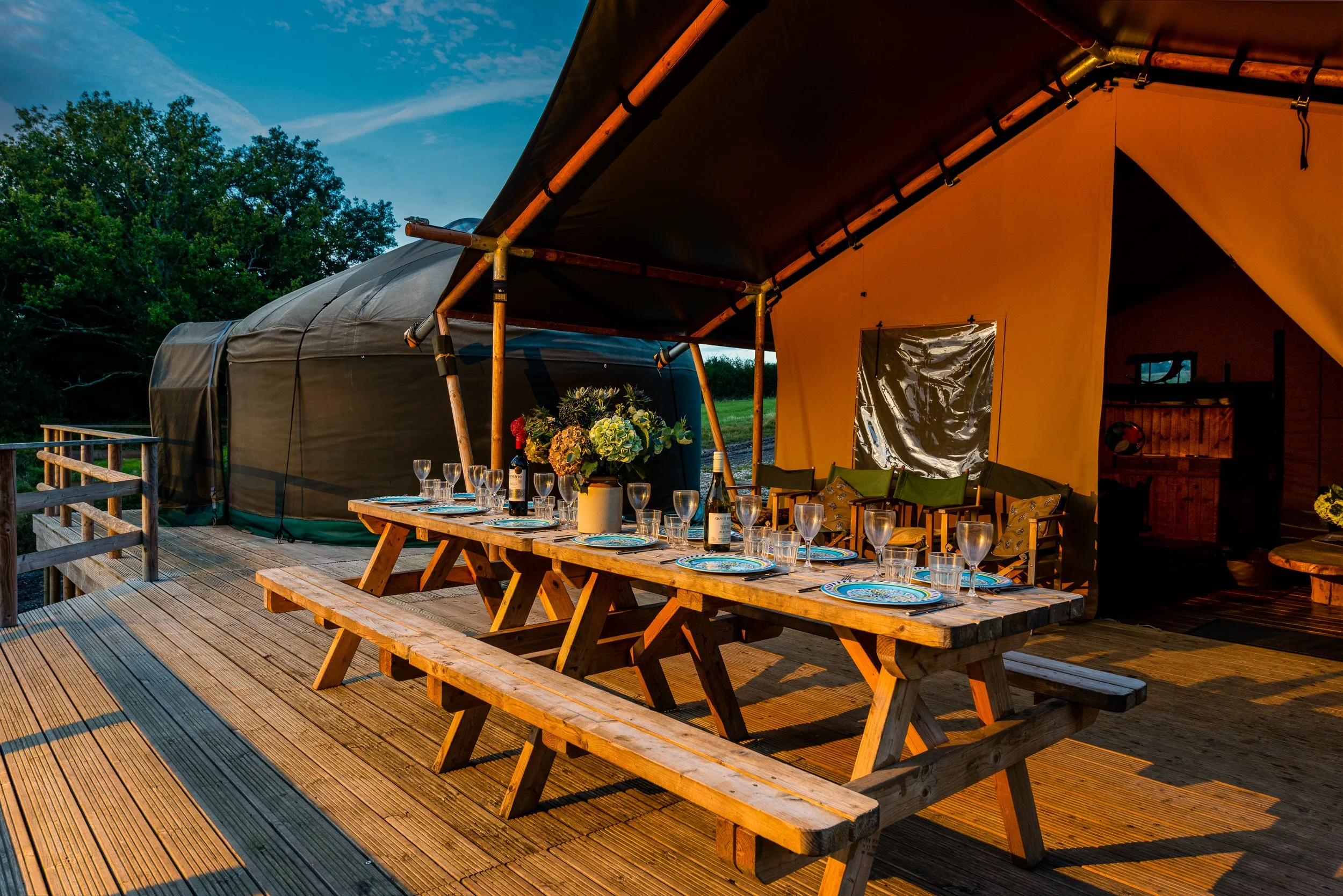 Exterior of a safari tent at Stock Gaylard, showing the large outdoor dining table set for dinner.