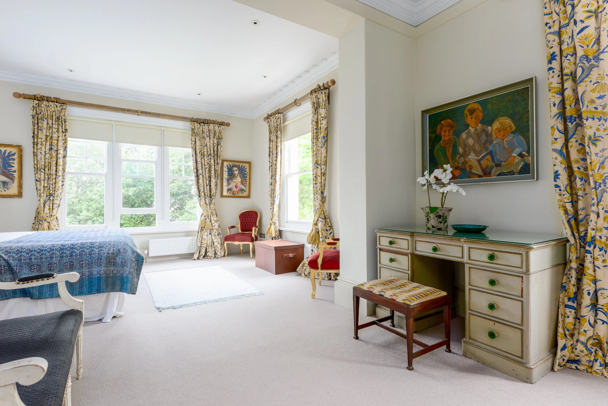 Character bedroom at The Pink House with antique furniture, patterned curtains, artwork and a large window overlooking the garden.