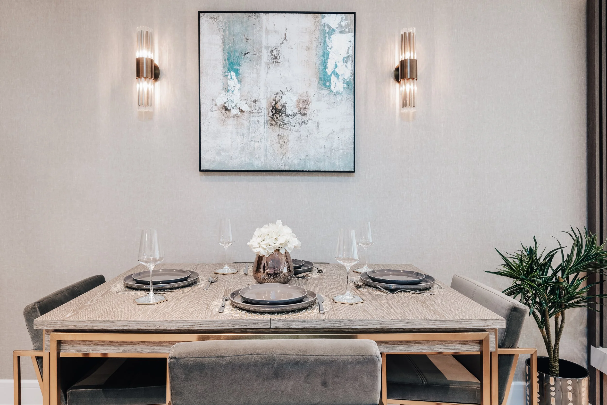 Contemporary dining area with styled table setting, artwork, wall lighting and modern interior finishes.