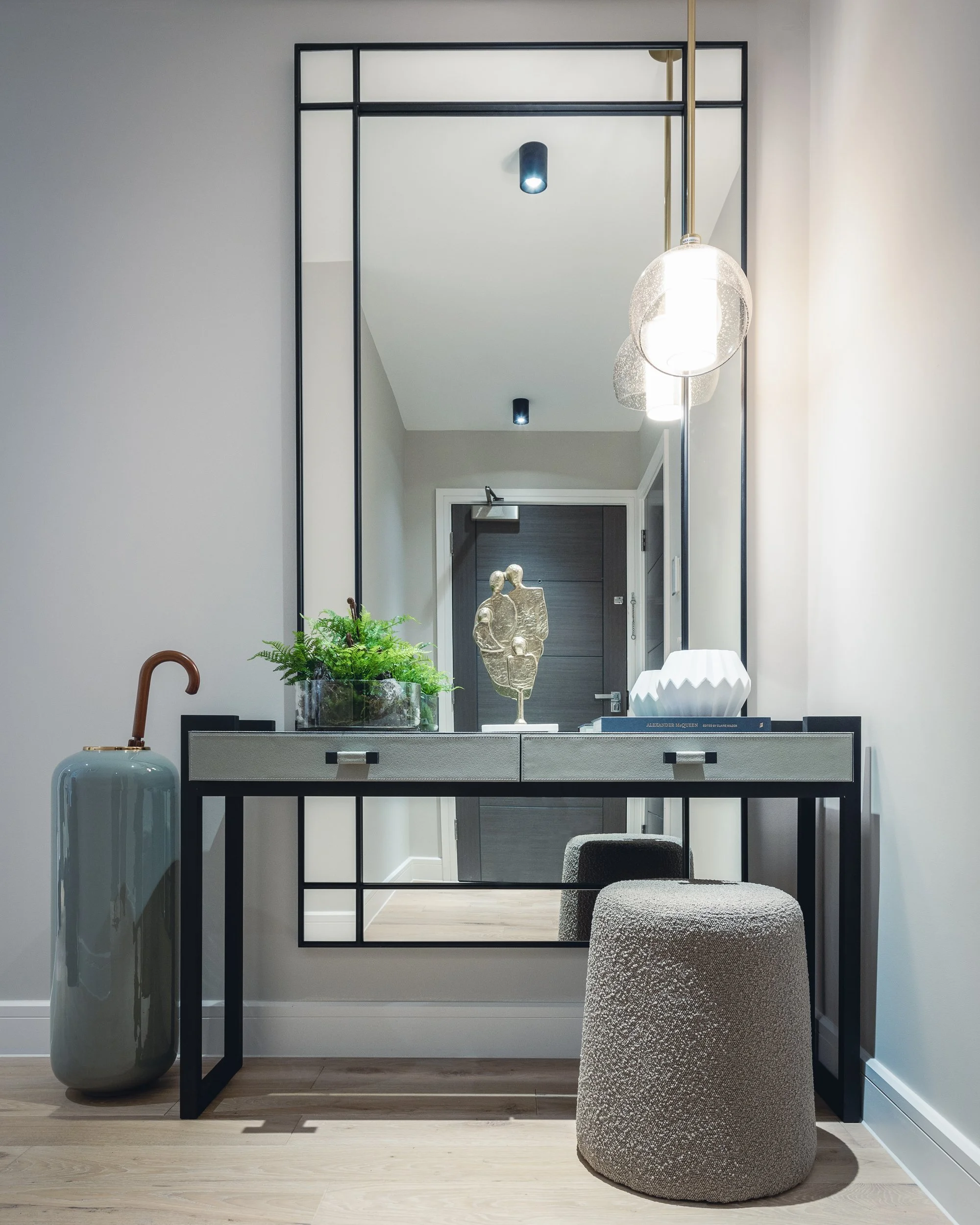 Contemporary hallway with console table, mirror, decorative accessories and modern pendant lighting.