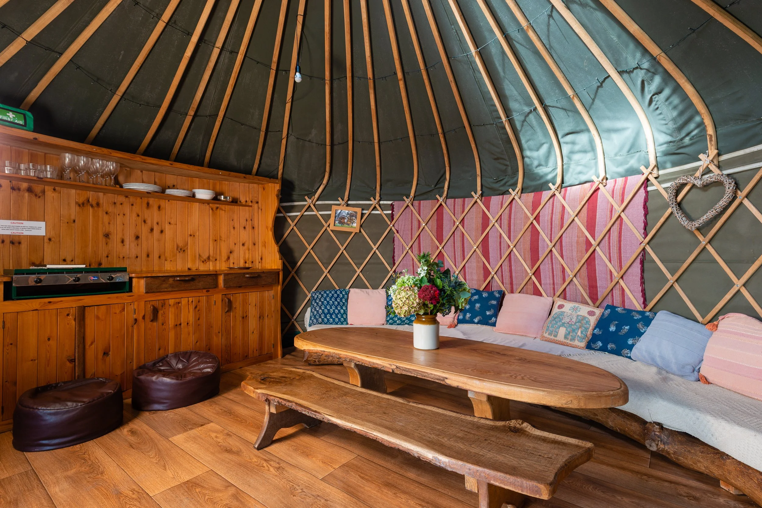 Interior of a glamping yurt at Stock Gaylard, showing timber flooring, seating and decorative fabric walls.