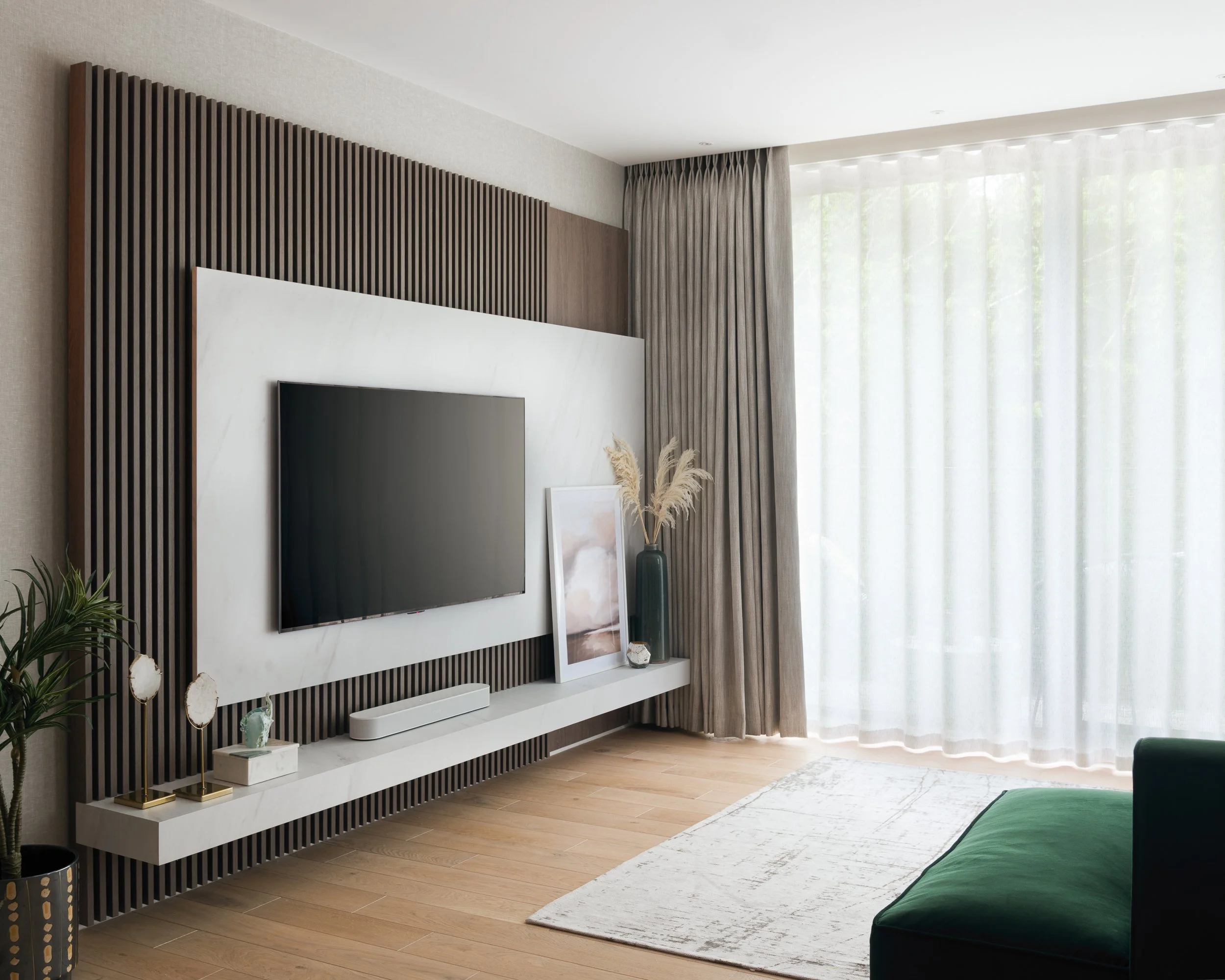 Contemporary living room feature wall with timber slatted panelling, wall-mounted television and bespoke joinery.