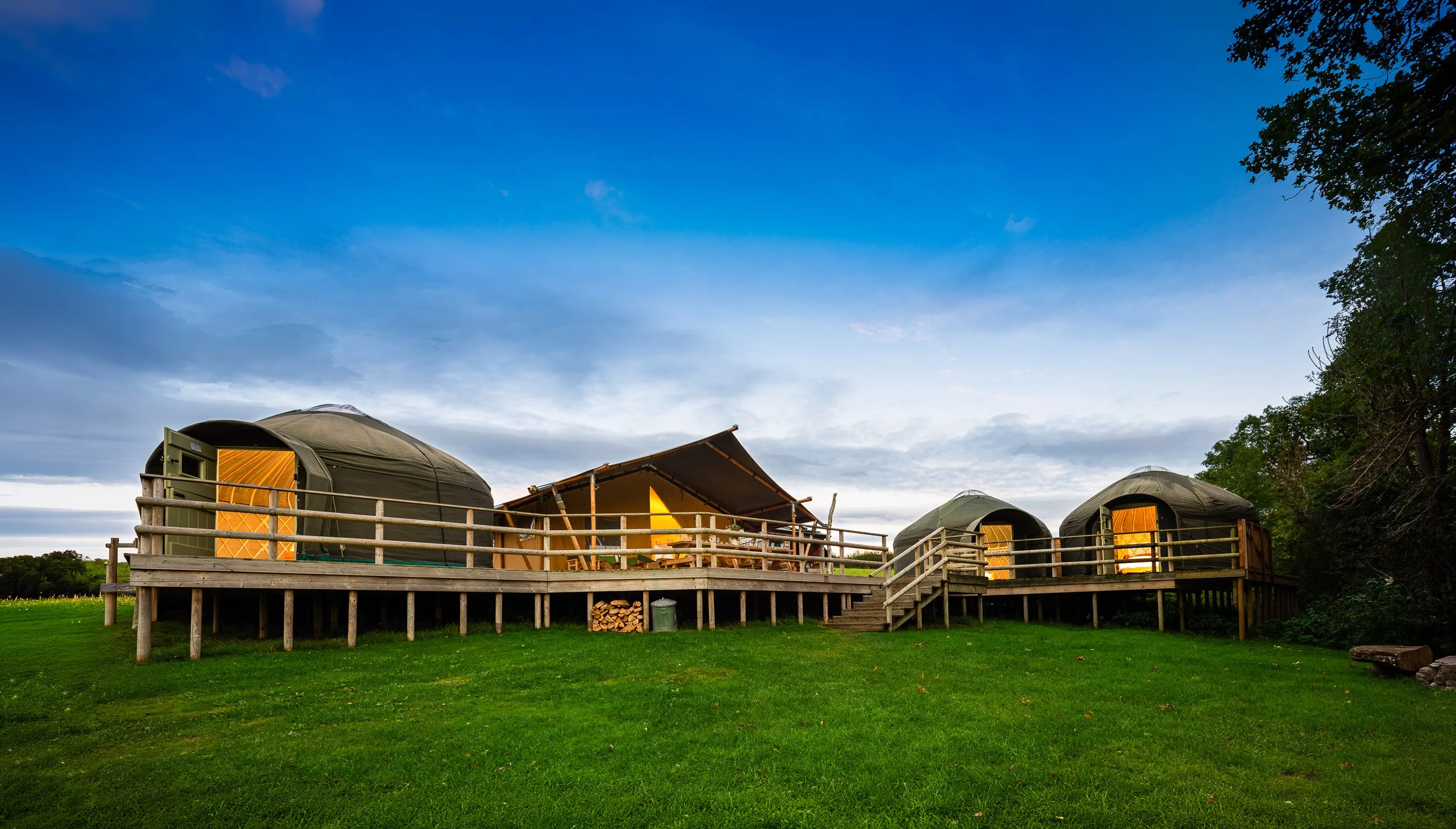 Glamping tents at Stock Gaylard photographed in evening light, showing the accommodation and surrounding open space.