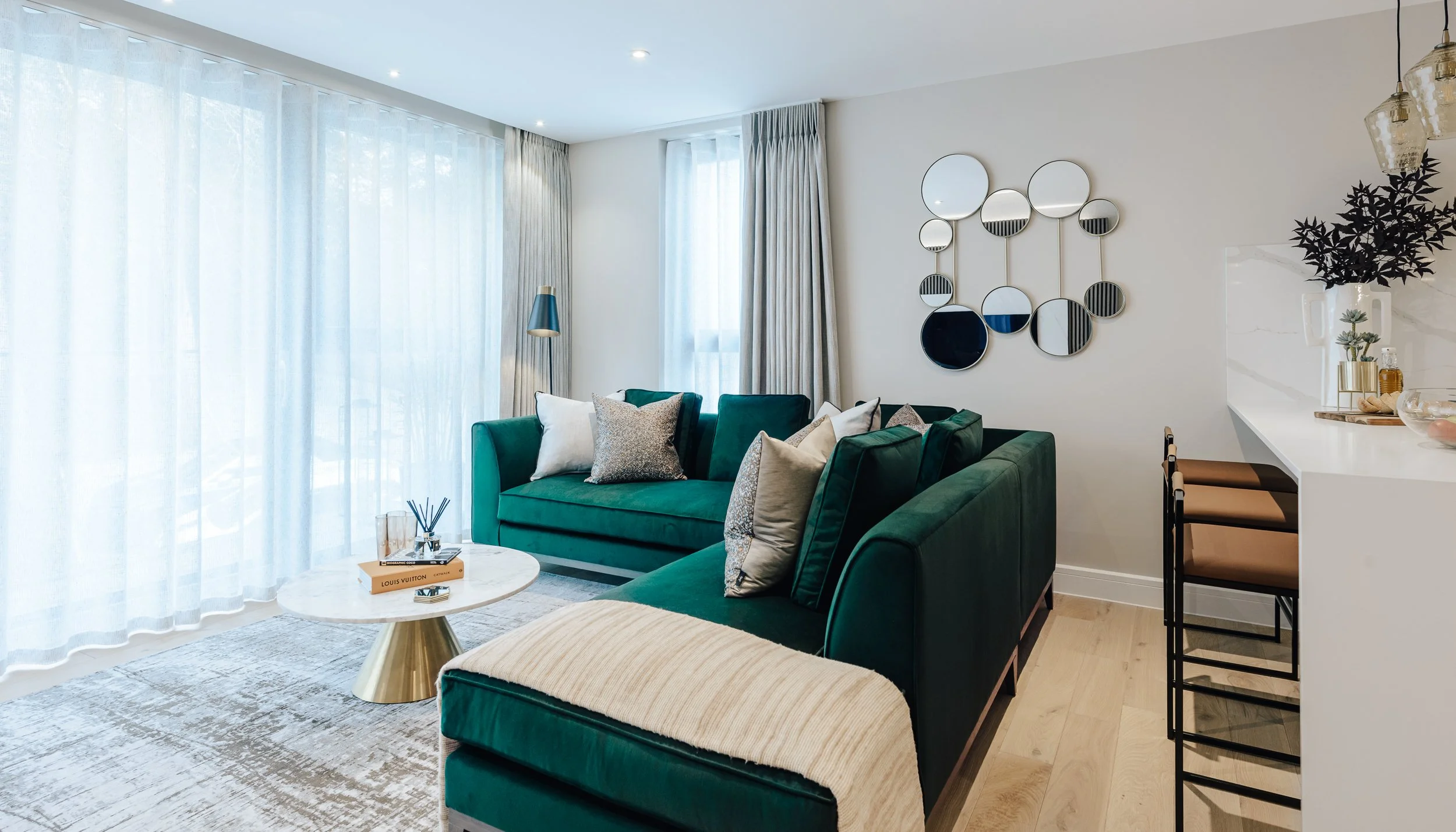 Modern living room with teal corner sofa, decorative mirrors, soft furnishings and open plan layout.