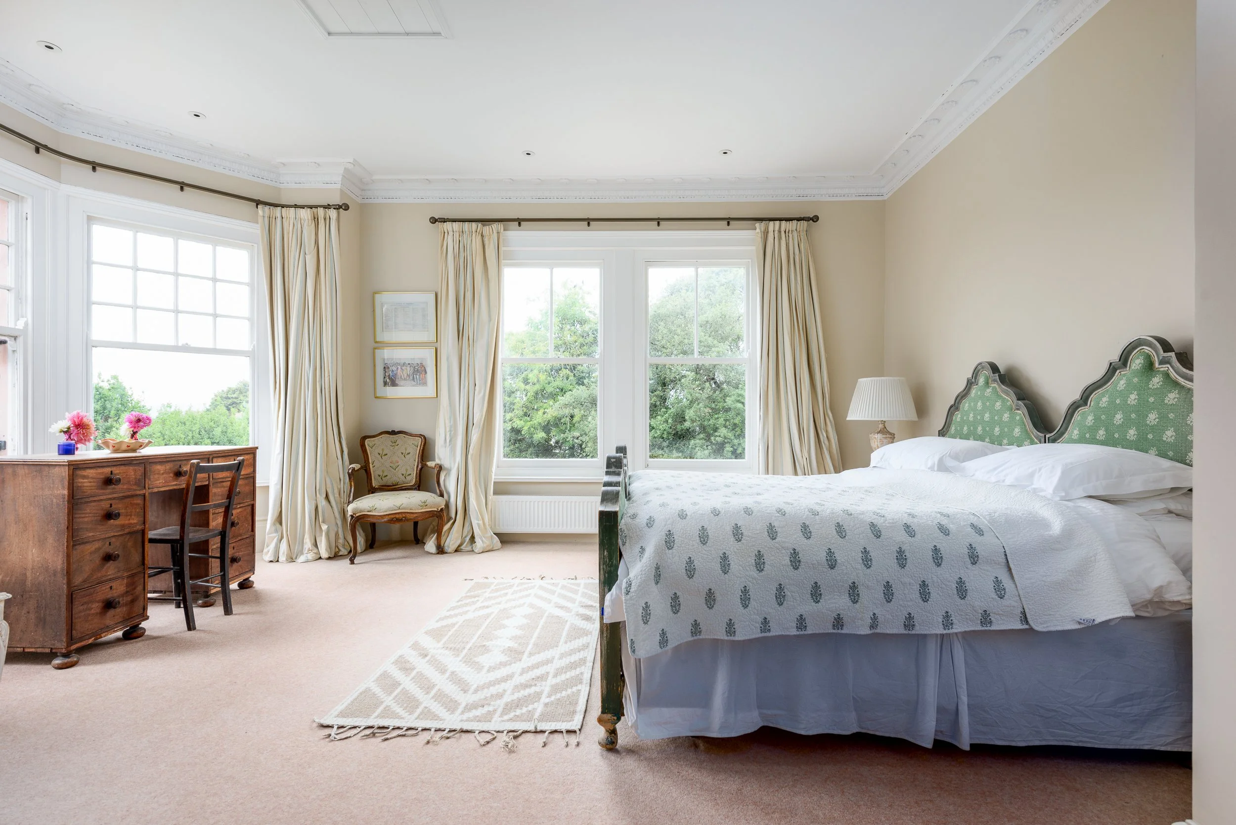 Spacious period bedroom at The Pink House in Bembridge, with bay windows, antique furniture, soft furnishings and natural light.