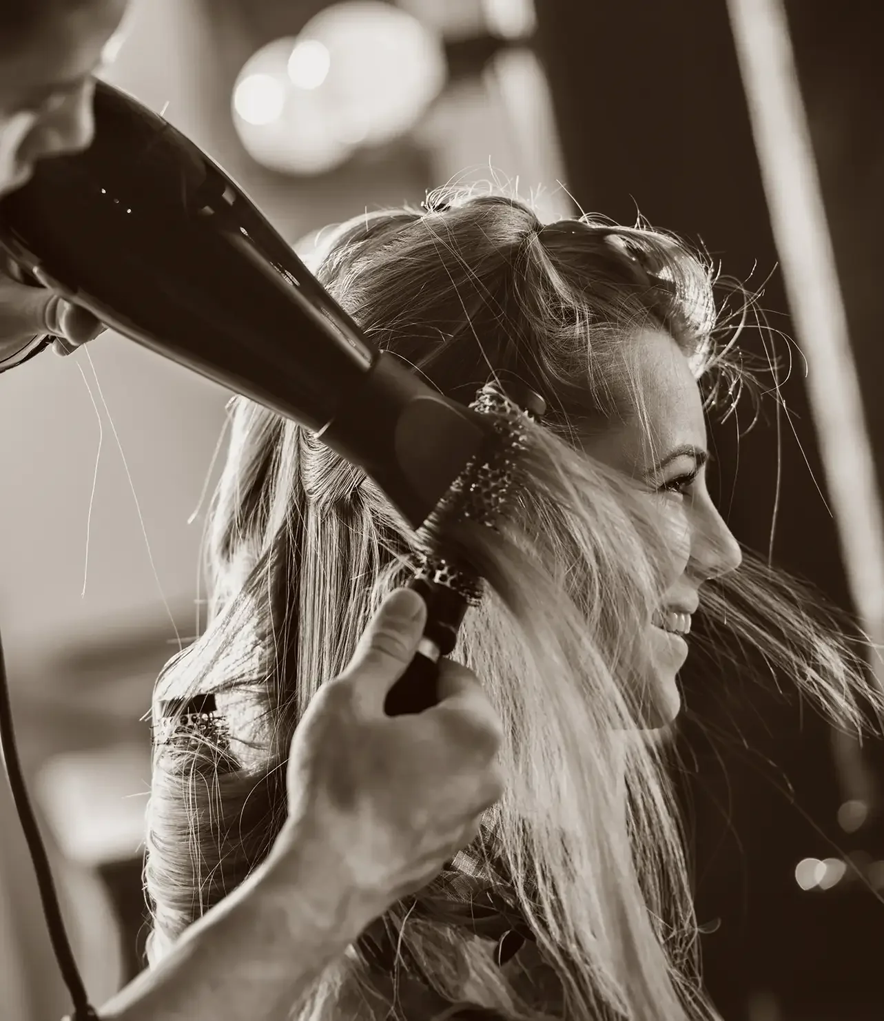 A woman is having her hair blow-dried by a stylist in a salon