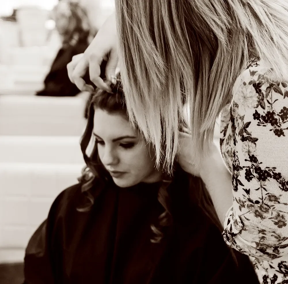 Hairdresser styling a client’s hair in Albert Fields hair salon, creating soft curls and professional finish