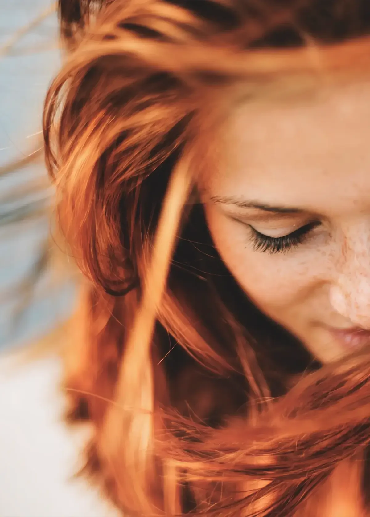 Close-up of a woman with long auburn hair falling softly across her face, styled with natural shine at Albert Fields salon