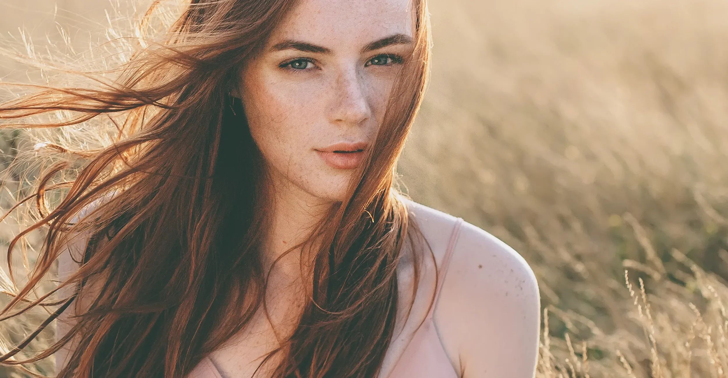Portrait of a woman with flowing auburn hair in natural sunlight, styled with a glossy finish from Albert Fields salon