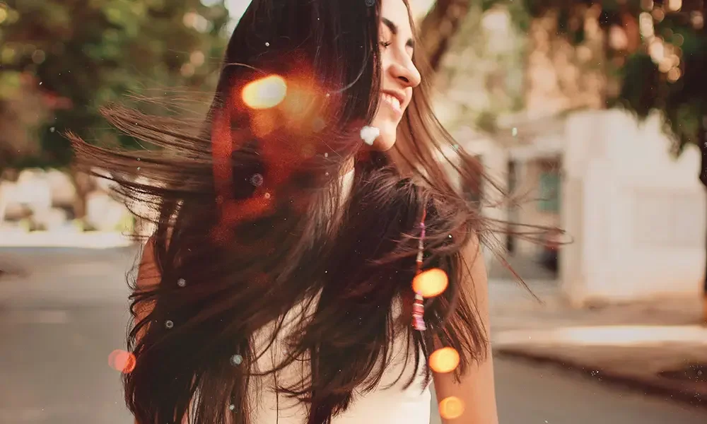 Woman with long dark glossy hair caught in movement outdoors, styled for natural shine at Albert Fields salon