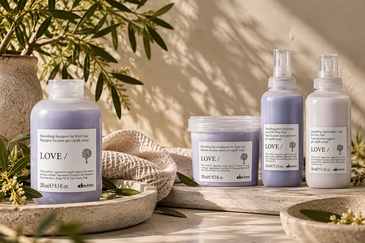 Davines LOVE haircare collection featuring shampoos, conditioners and styling products, arranged with natural stone, soft linen and botanical greenery.