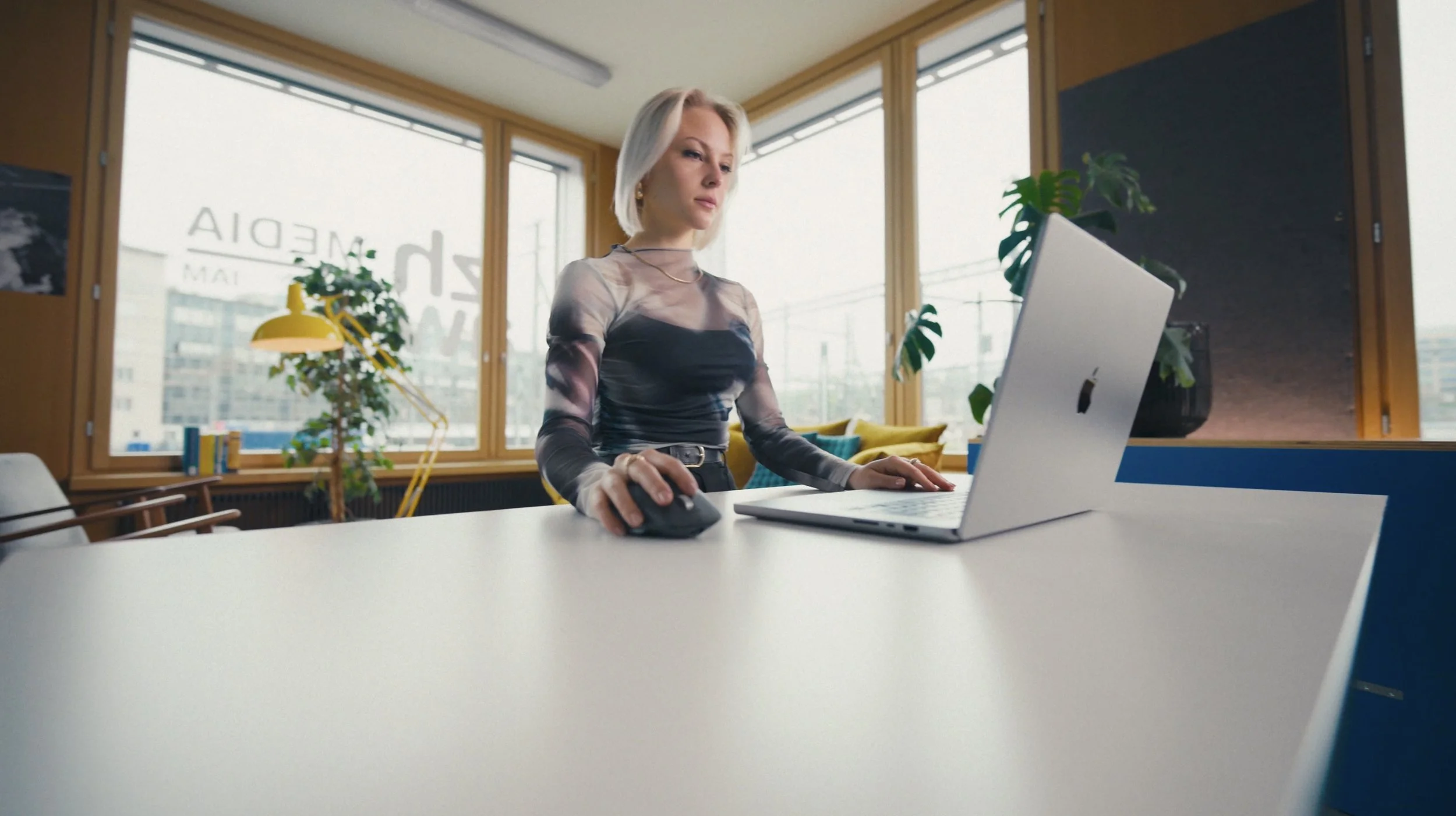 Frau arbeitet an einem Laptop im Büro, umgeben von Pflanzen und großen Fenstern mit Stadtblick.