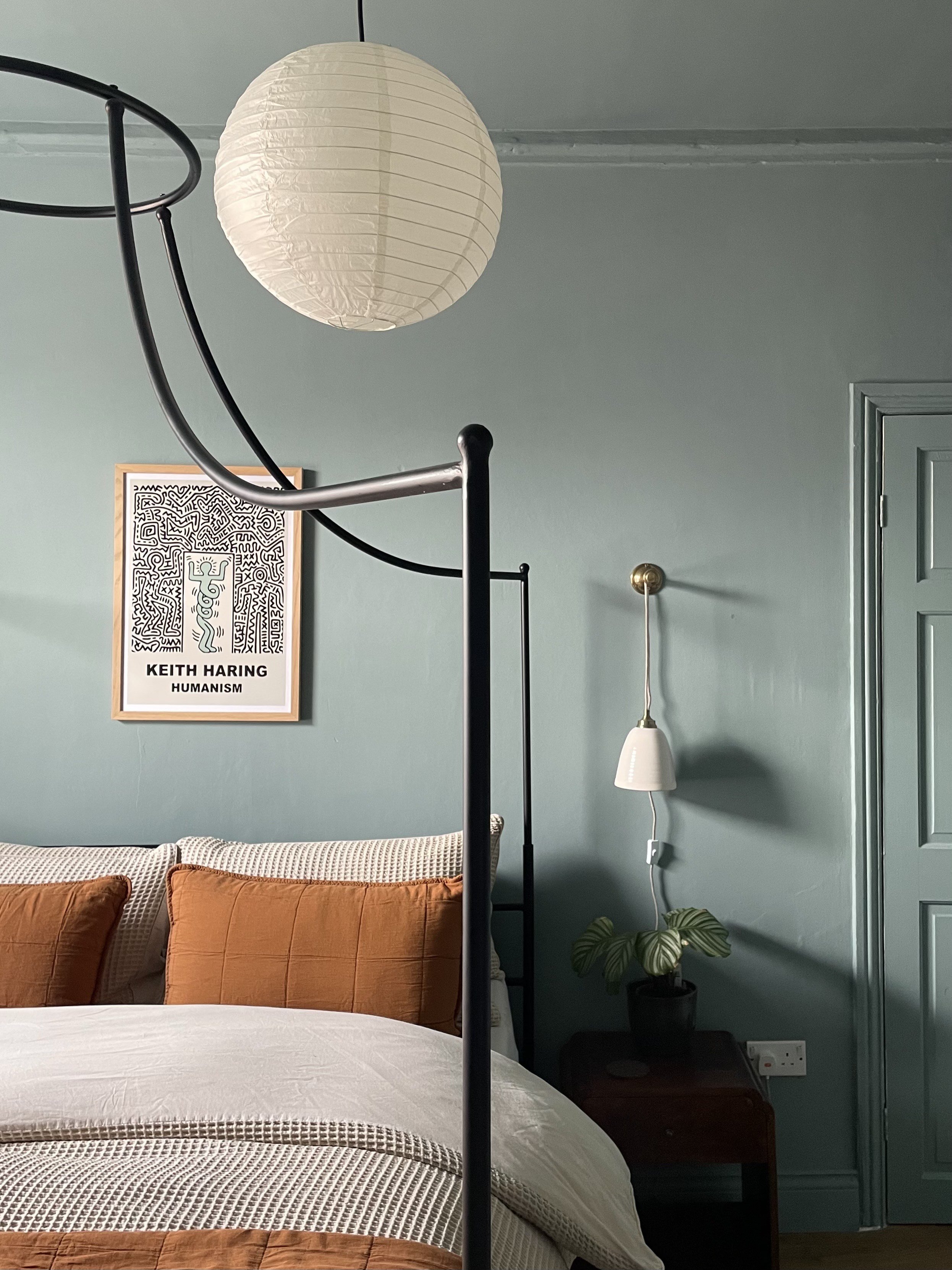 A teal bedroom with an orange bedspread
