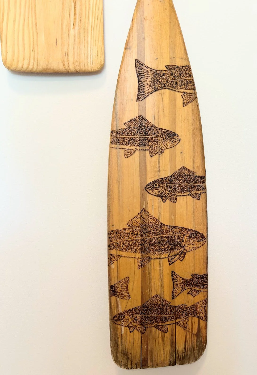 Wooden paddle with fish engravings.