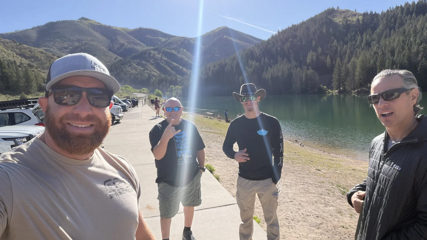 Four members of the Fathom crew at the edge of Tibble Fork Reservoir with the water and mountains behind them