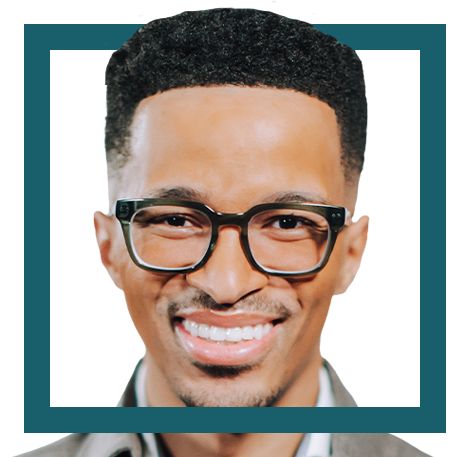 Close-up of a smiling man wearing glasses and a collared shirt.