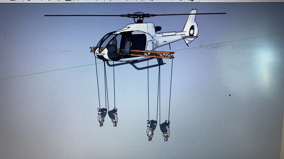 A helicopter equipped with ropes for rescue operations, with four rescue harnesses hanging from it.