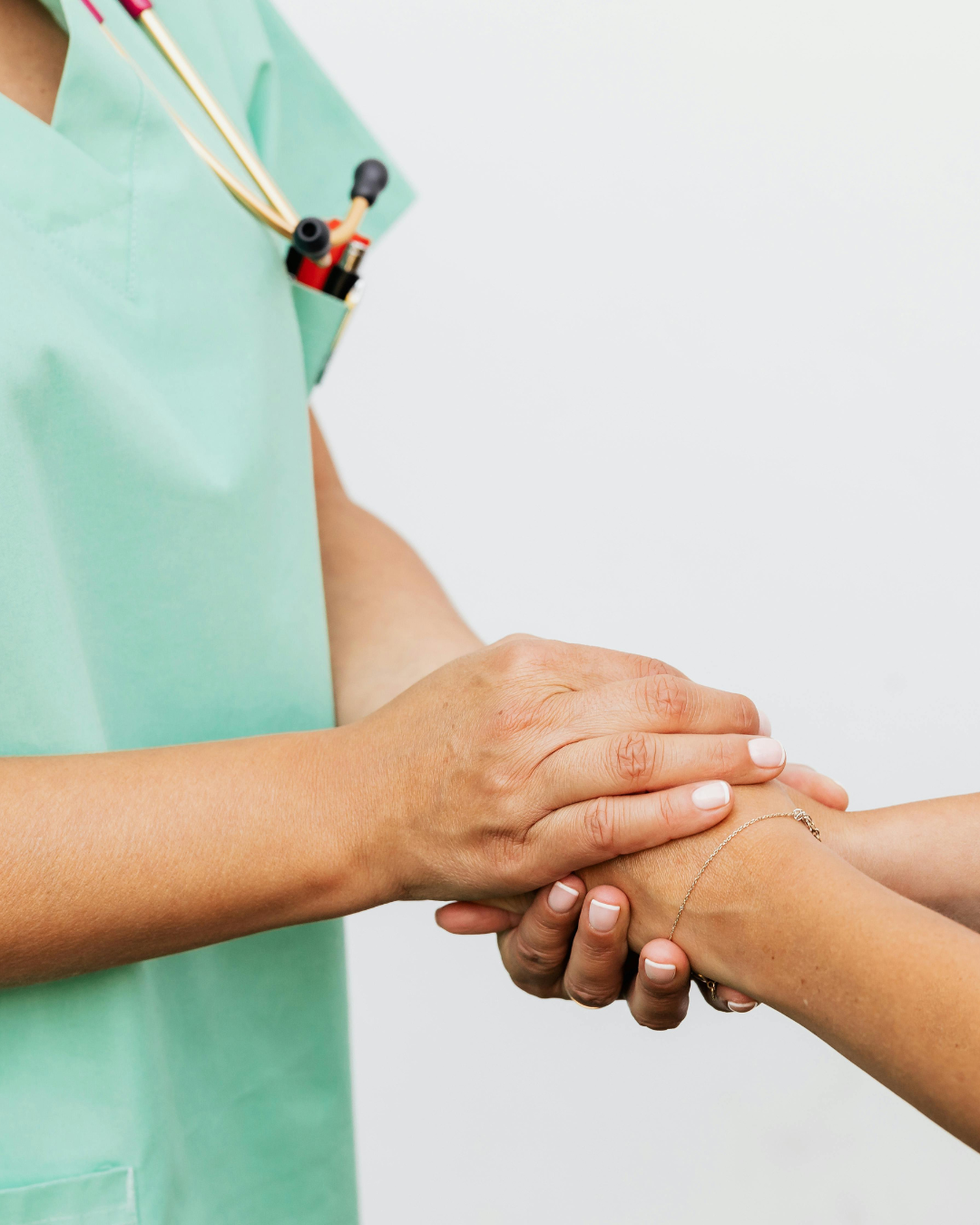 Medical professional holding a patient's wrist in a clinical setting.