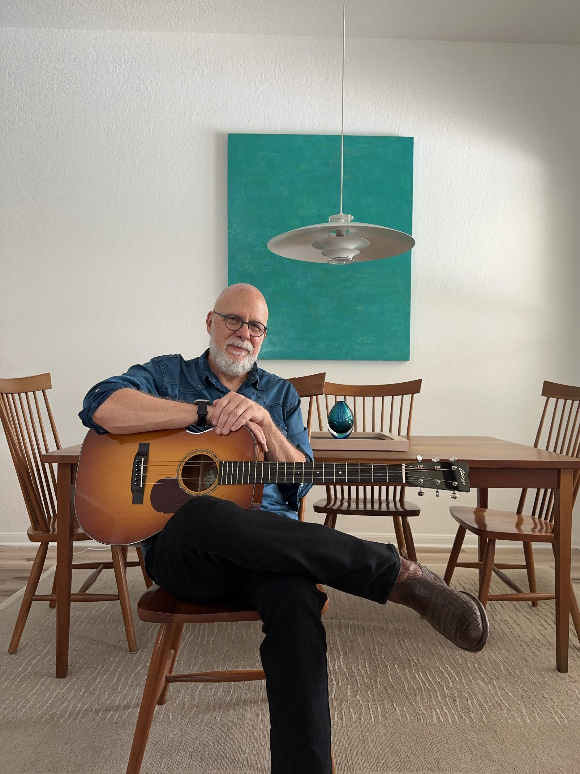Glenn seated, holding guitar