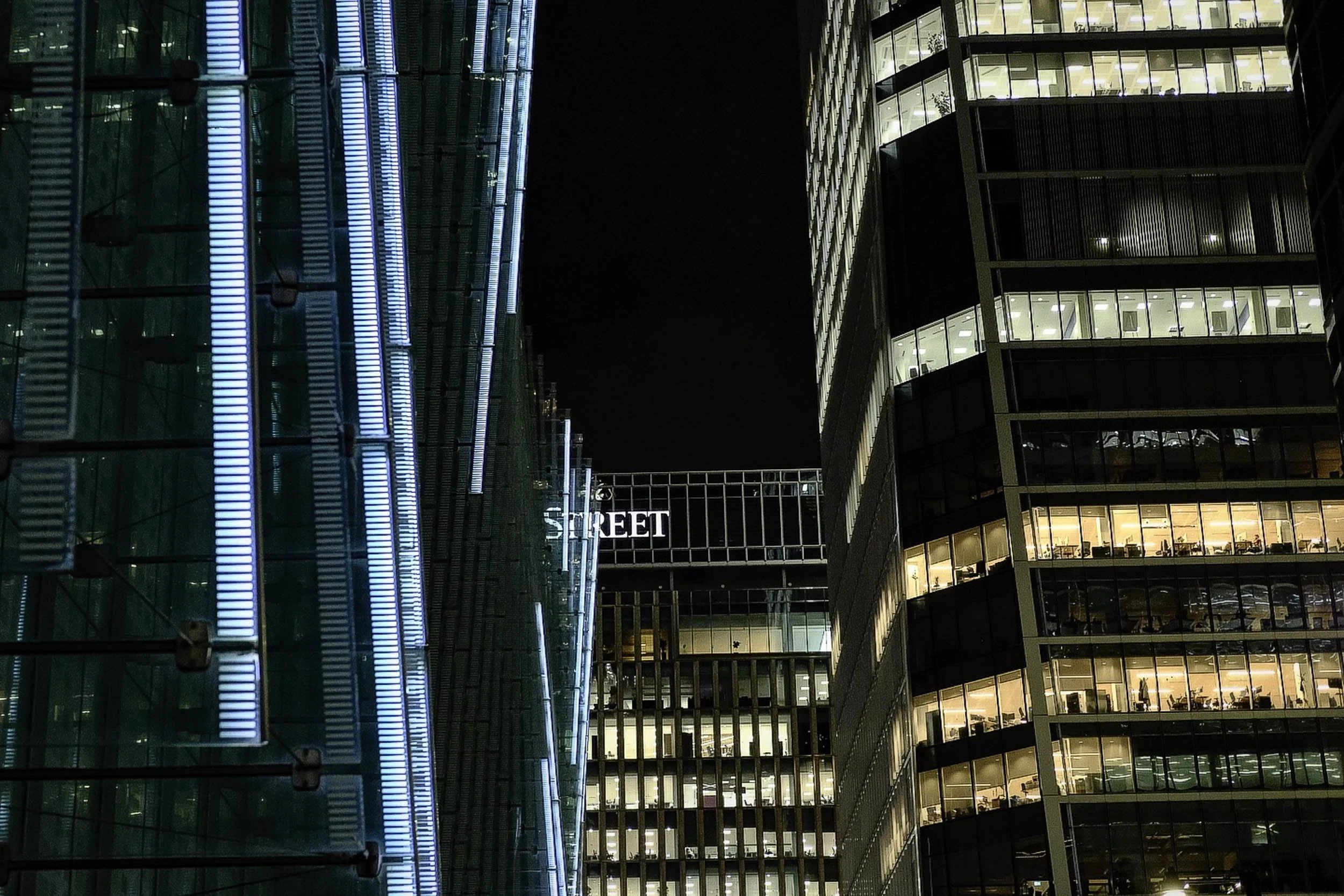 Neon glow from canary wharf buildings at night in London with the word Street illuminated