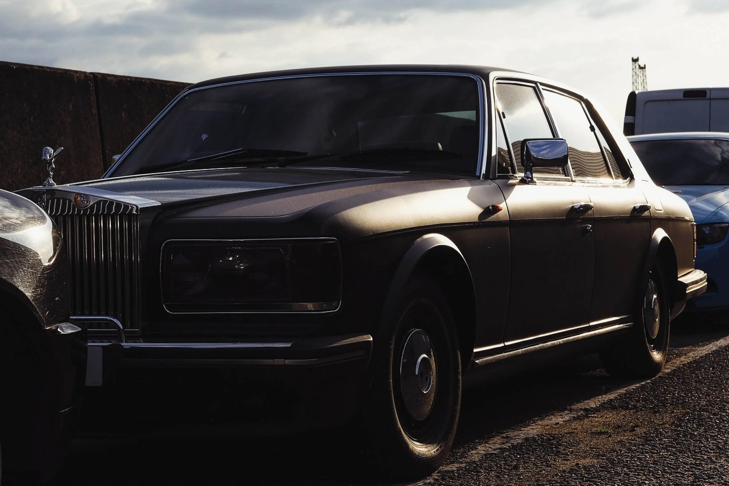 Rolls Royce discreetly parked in an industrial estate in east london with matte purple paint reflecting in the sunlight