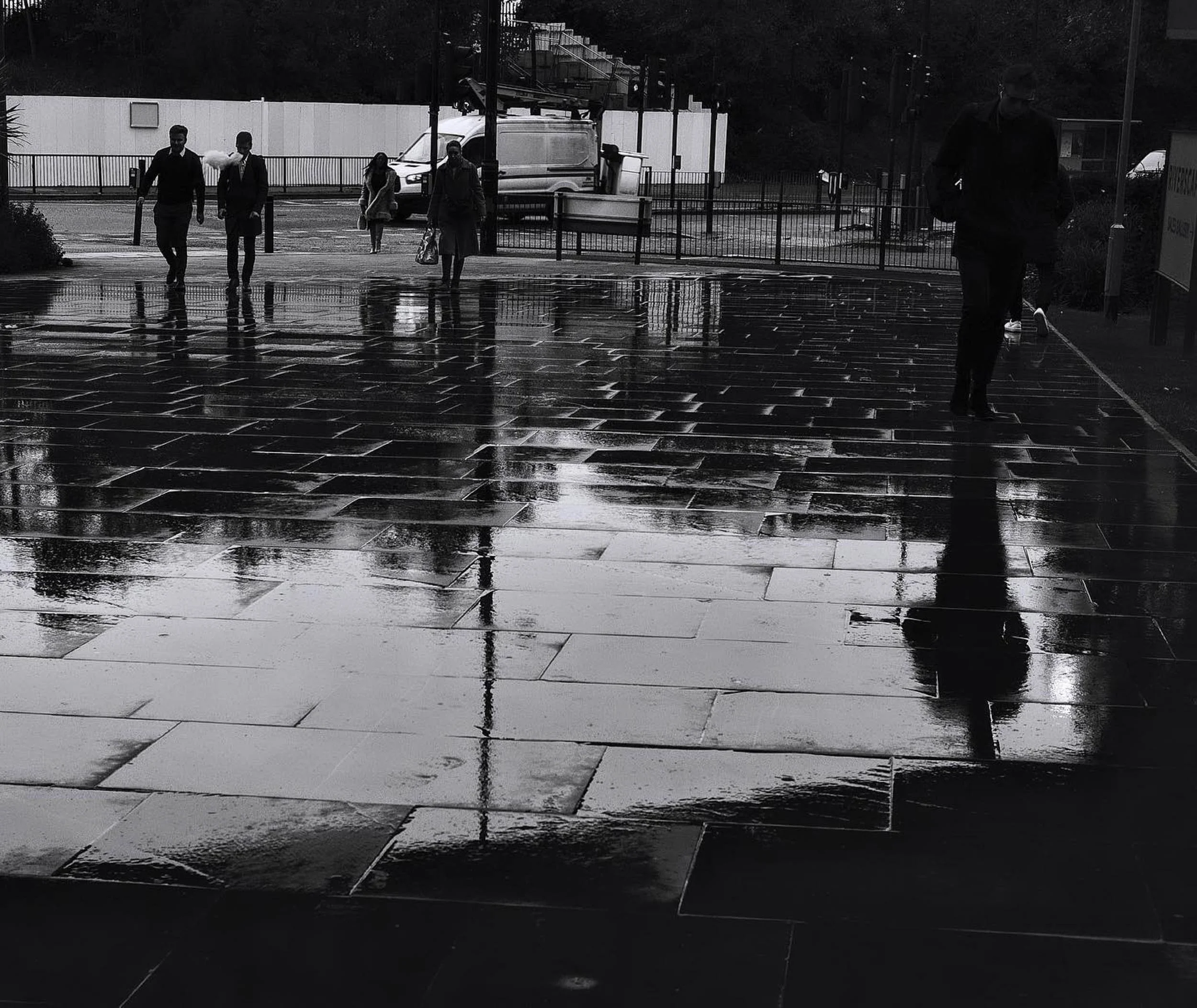 Black and white rainy day in london as passers by create reflections in on the wet ground