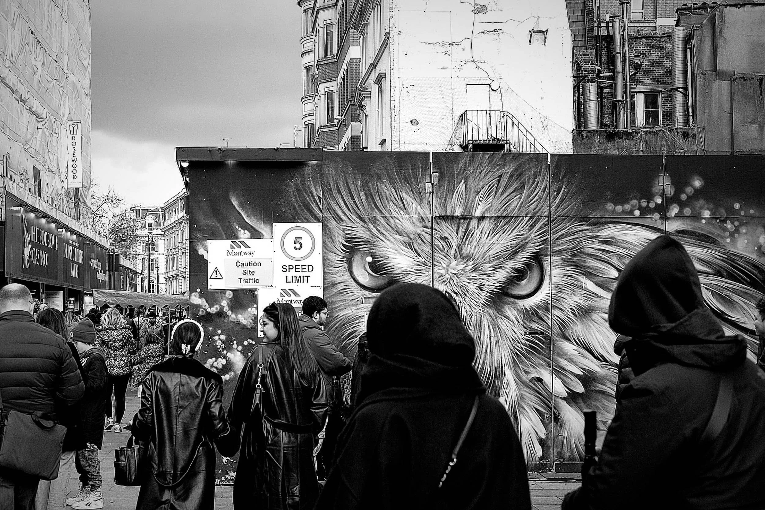 Busy black and white street scene with graffiti eagle eyes watching passers by in London