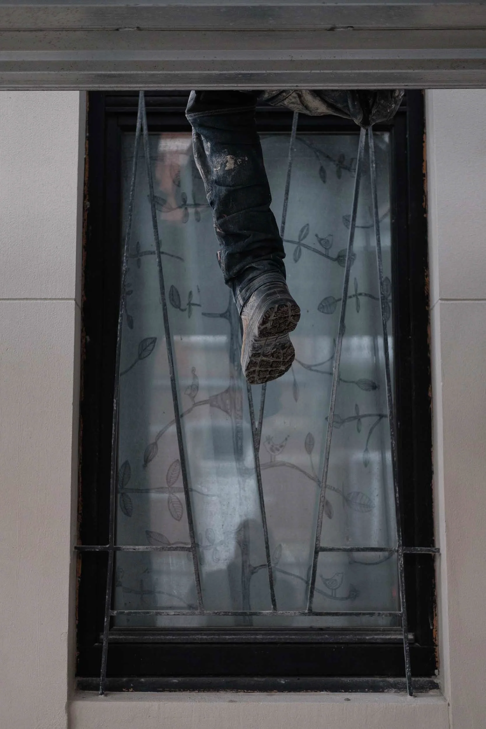 Humours and abstract scene of a window and a construction workers leg dangling from above as if a surreal painting