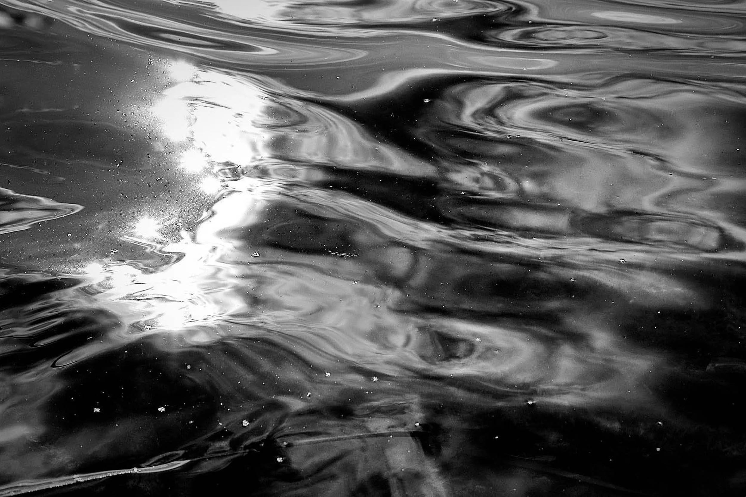 Abstract black and white reflections on the surface of water glistening in the sunlight like an abstract and surrealist painting