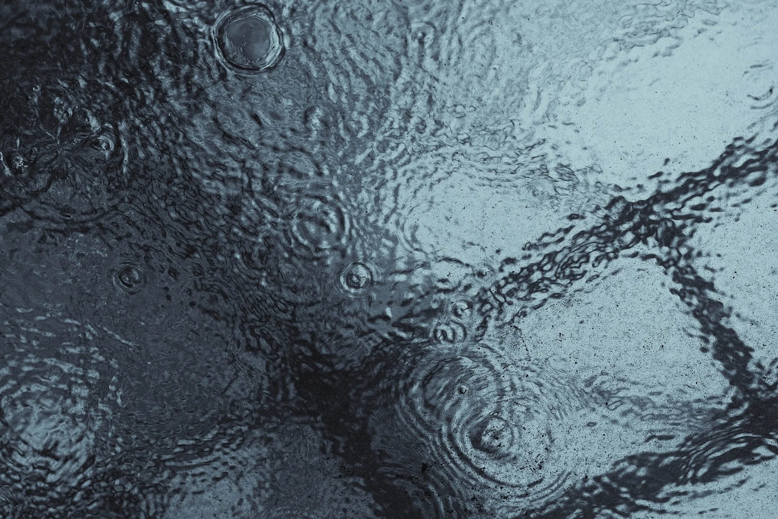Rain in London seen from below in a cool colour tone and abstract detail of droplets