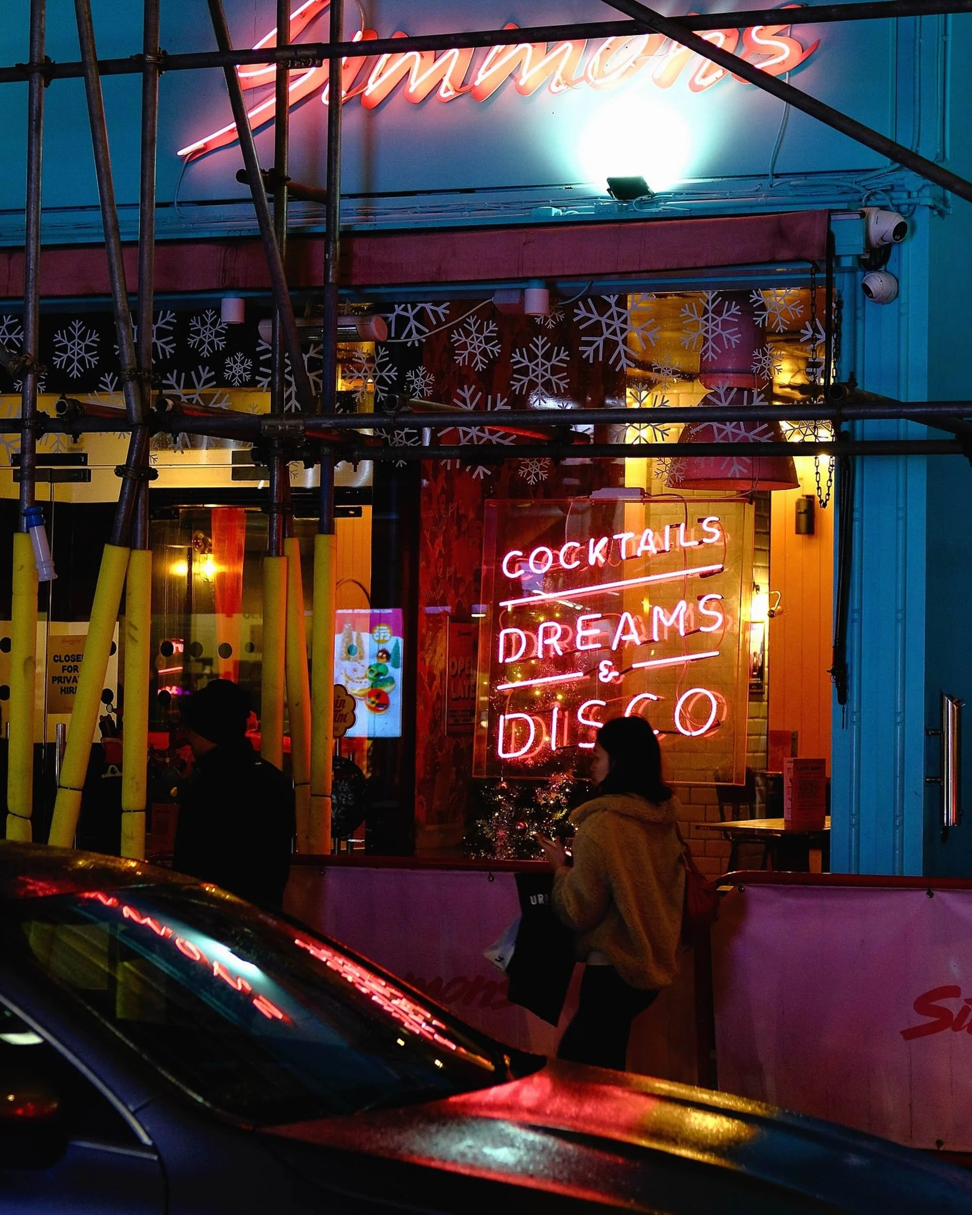 Soho London at night in rain with neon signs glowing and reflections from car with passes by in motion blur