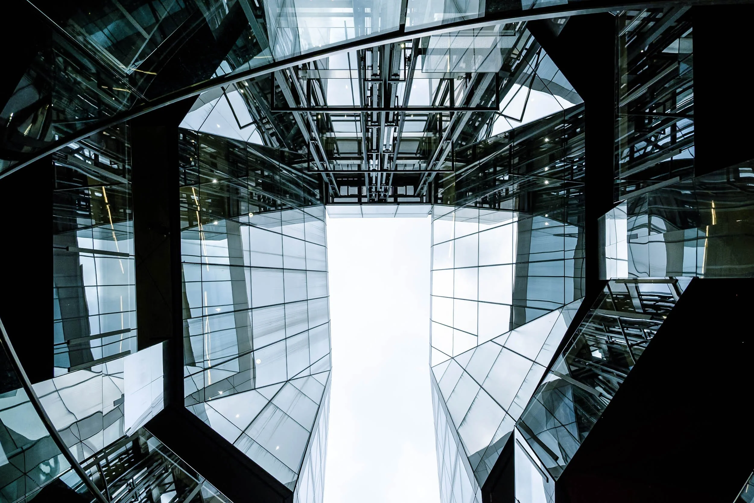 Geometric symmetry and reflections of glass filled architecture in London looking up