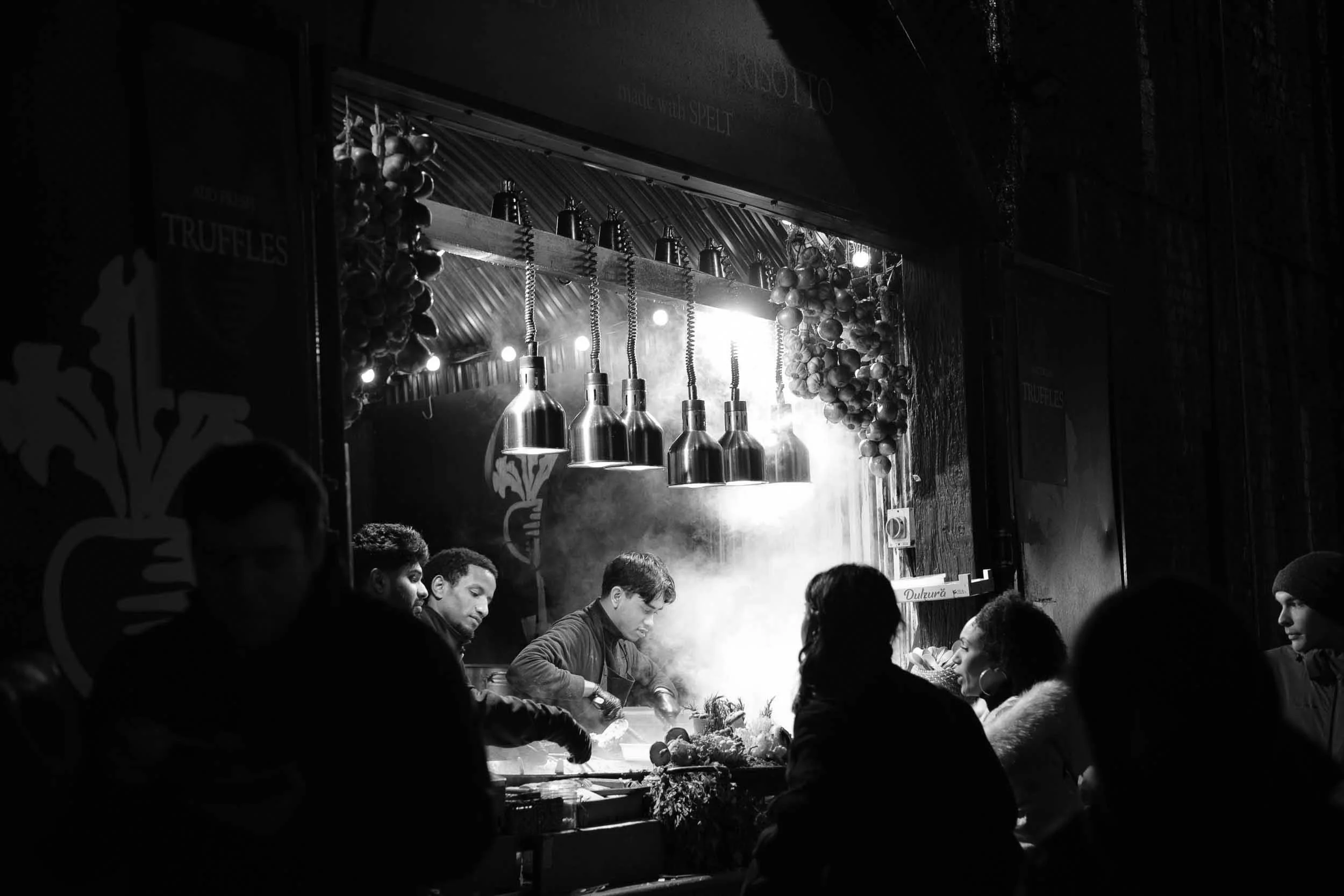 High contrast black and white scene at Borough Market London of street food kitchen and passers by in steam