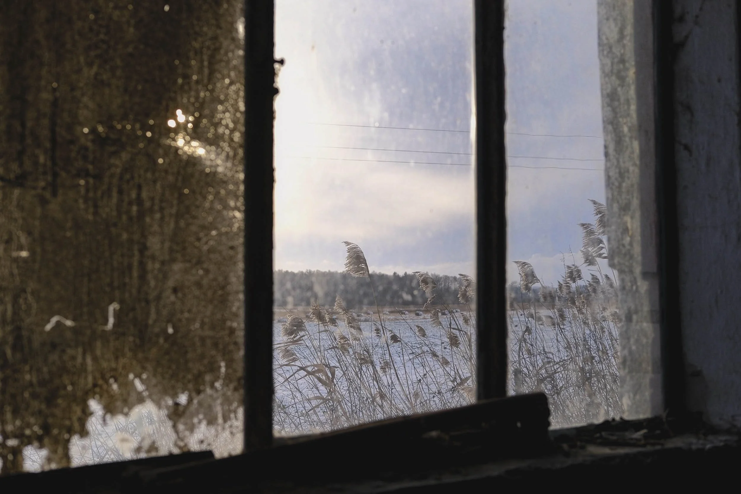 Warm winters sun show breifly on a cold winters day looking through an old industrial window to outside snow covered fields