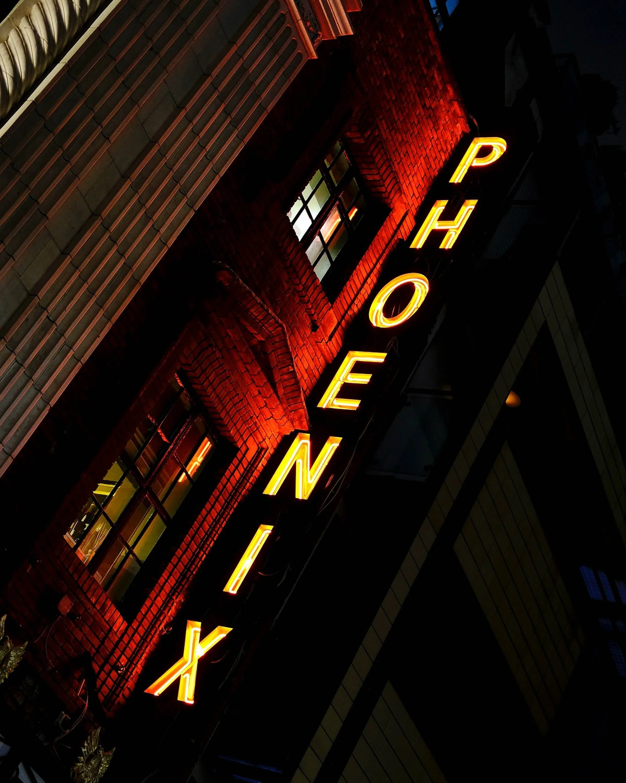 Red neon sign at night in London reflects onto the building and across windows in an abstract scene like an oil painting