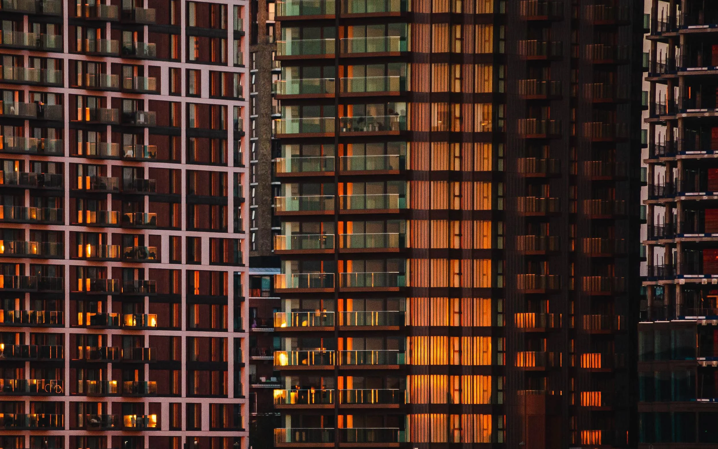 Geometric mosaic of glass fronted tower blocks in London reflect warm sunrise colours of golden hour like a patchwork of glass