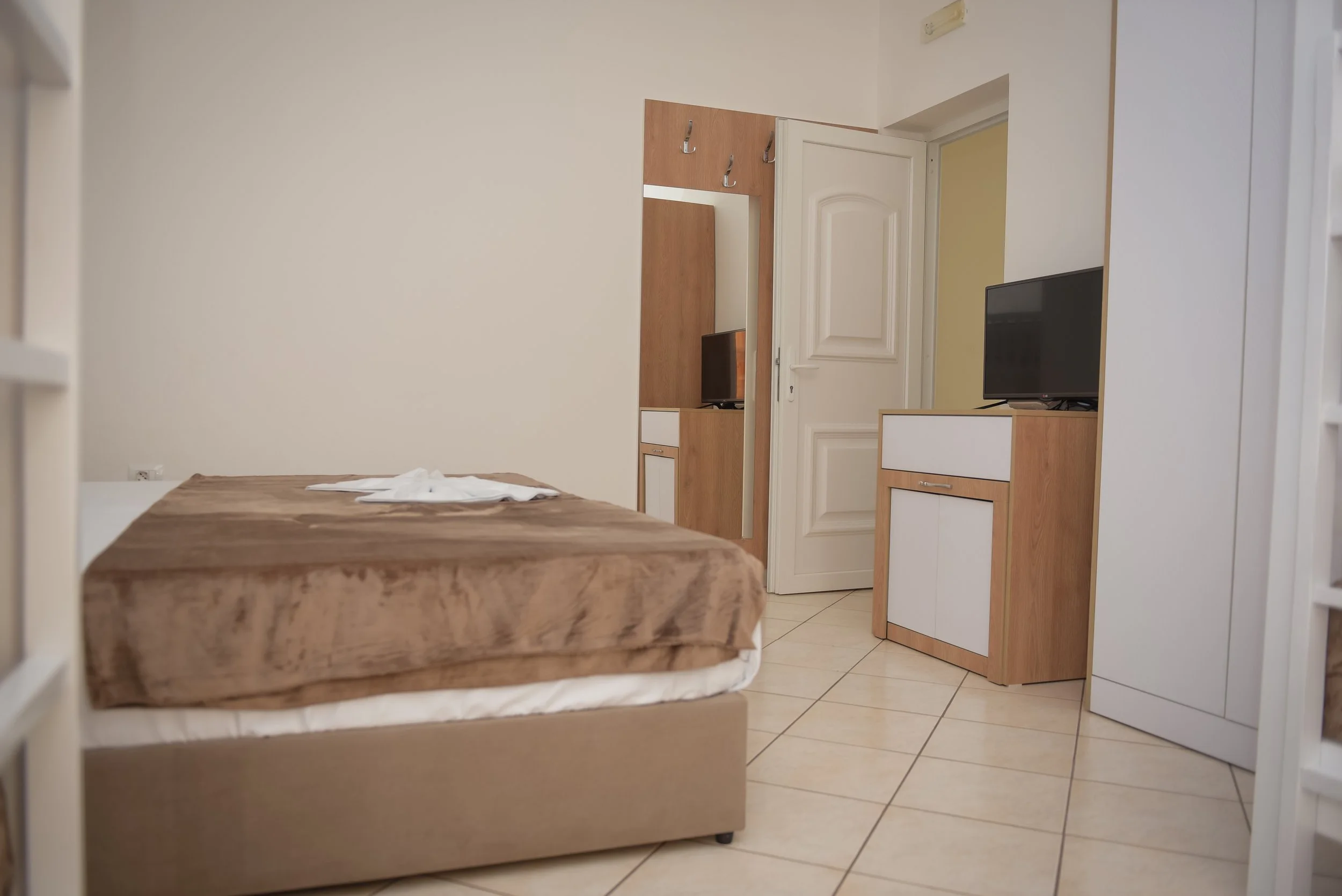 Interno di una stanza con letto, armadio, televisione e porta