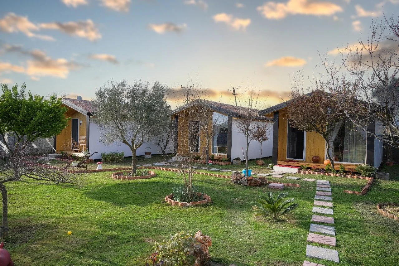 Casa di campagna con giardino ben curato, alberi e una strada di pietre che conduce all'ingresso.