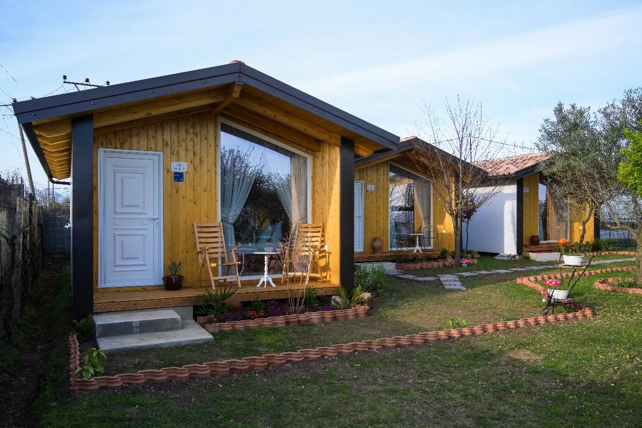Tre case di legno con giardino curato, piastrelle e piante decorative.