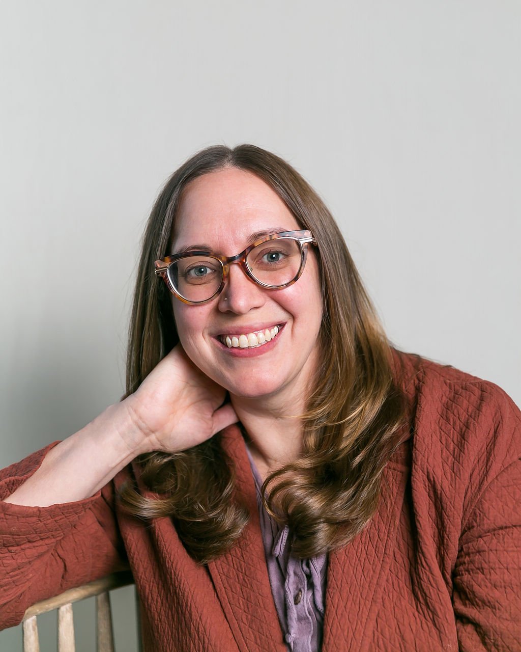 Rachael Benjamin, LCSW, therapist—smiling with her head resting gently on her hand.