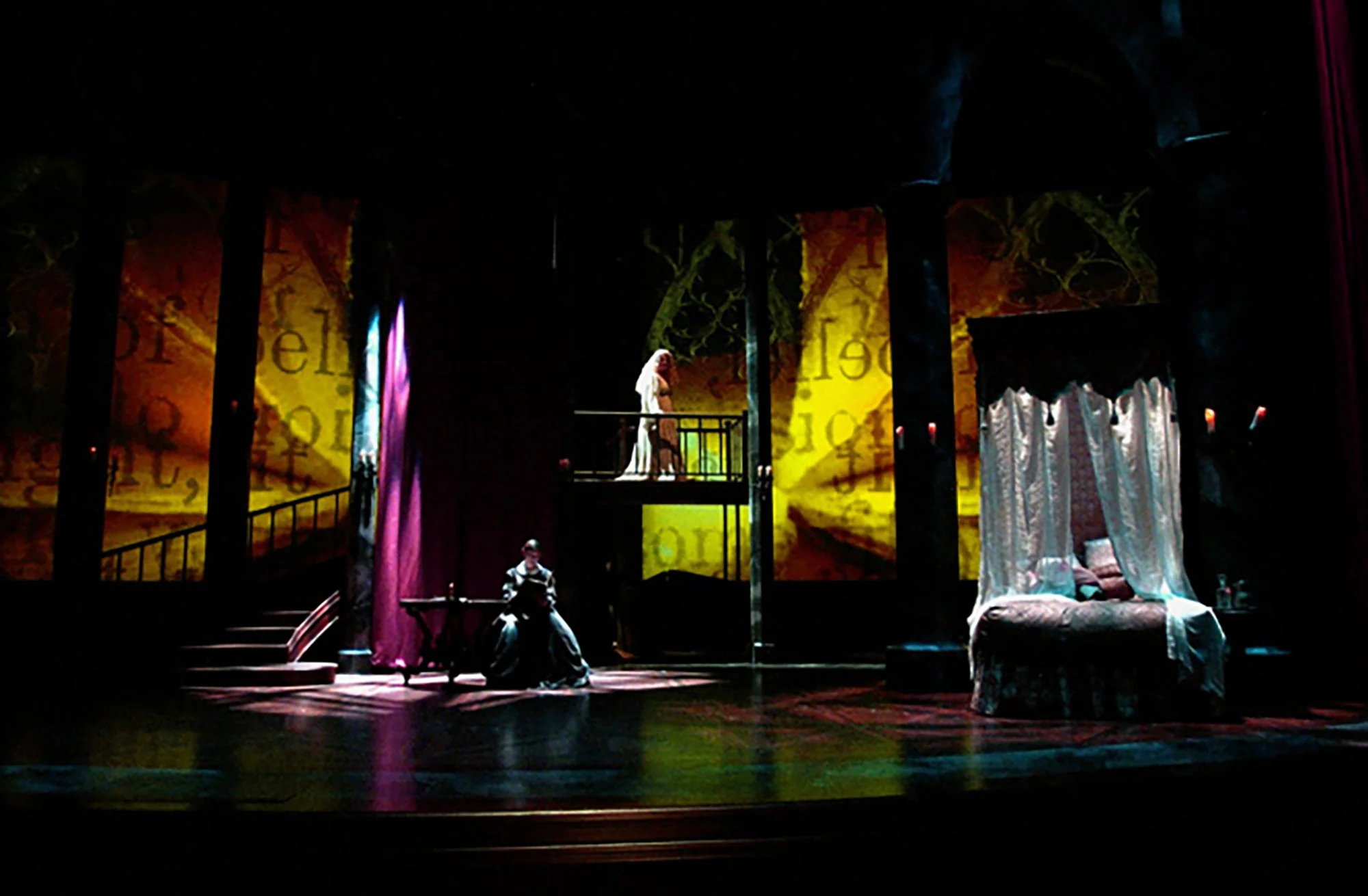 Theatrical stage with actors, colorful curtains, seating, and a large, illuminated backdrop with text.